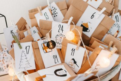 Selbstgemachter Adventskalender in Tütchen verpackt an einer Schnur mit Klammern befestigt und bunten Bildern.