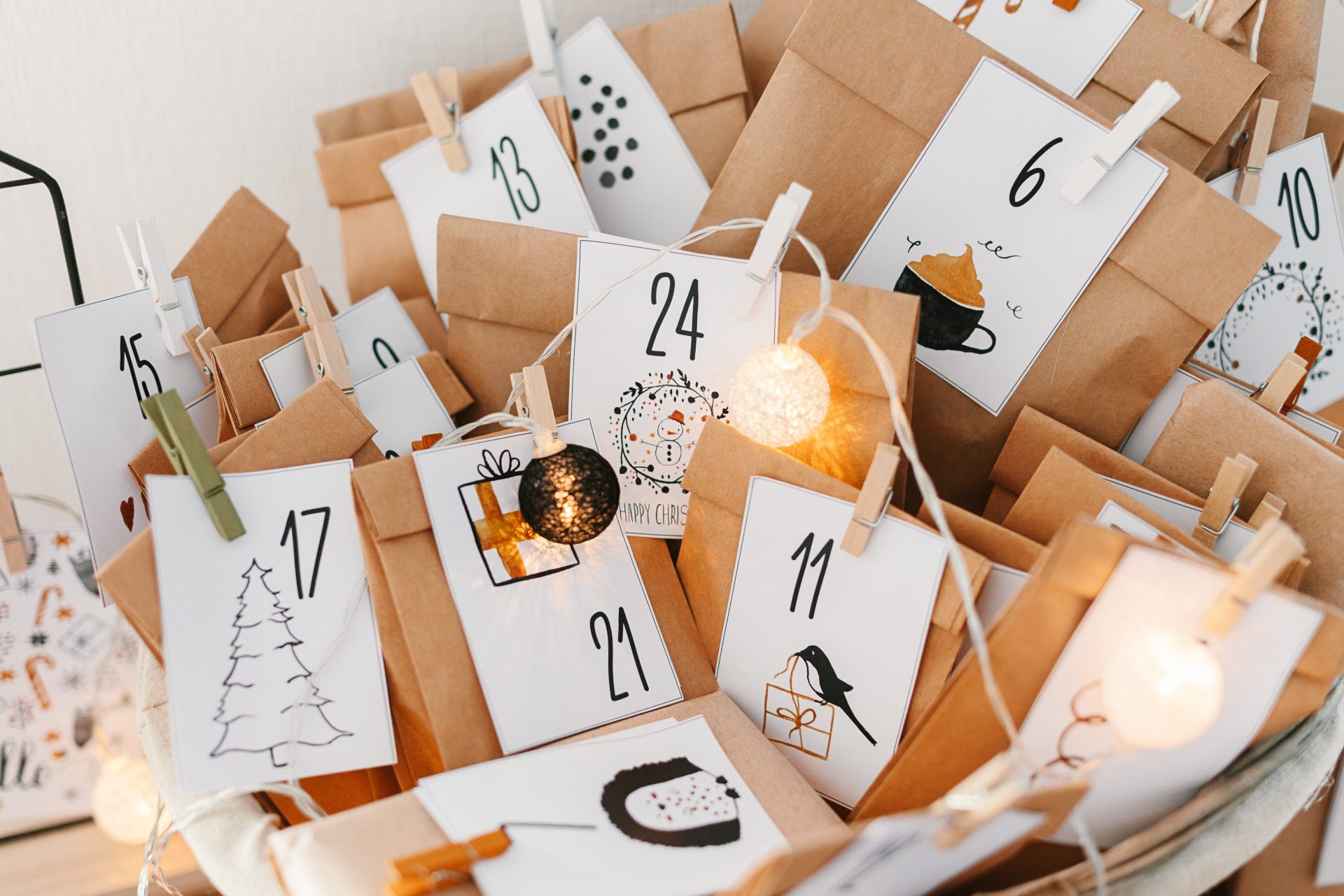 Selbstgemachter Adventskalender in Tütchen verpackt an einer Schnur mit Klammern befestigt und bunten Bildern.