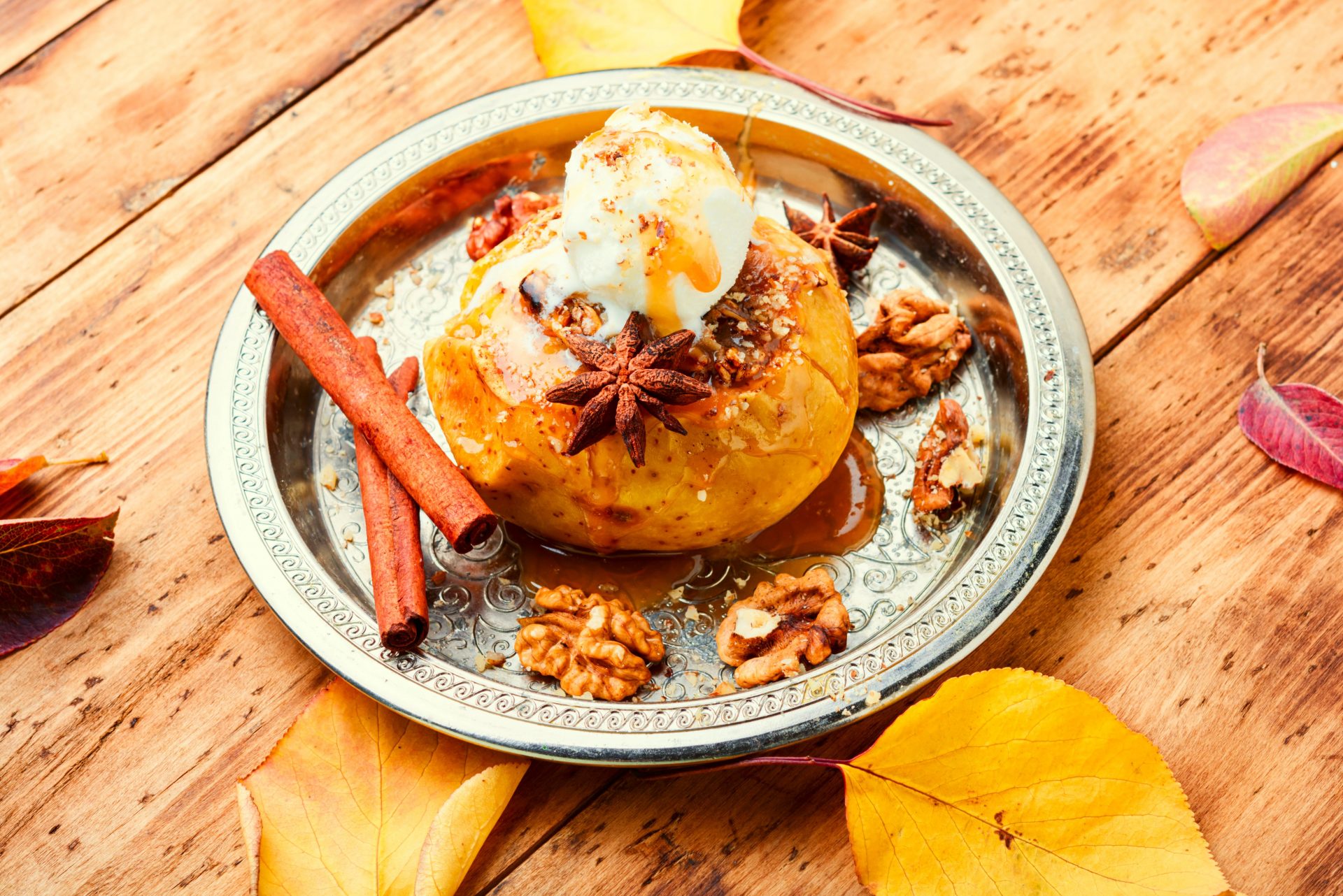 Ein Bratapfel mit Vanilleeis, einer Zimtstange und Wallnüssen dekoriert